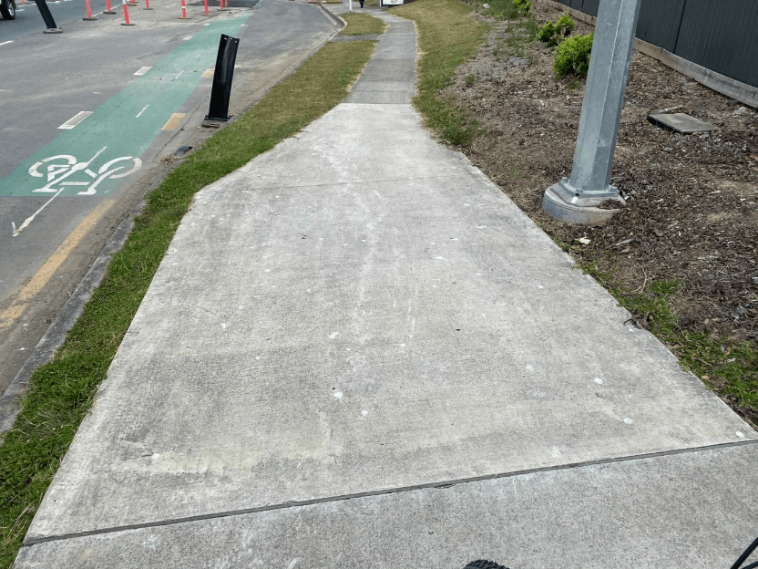 A sidewalk with grass and a sign AI-generated content may be incorrect.